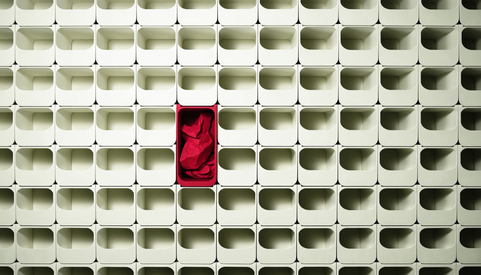 A wall of empty wooden pigeonholes, one of them holding a single crimson folder.